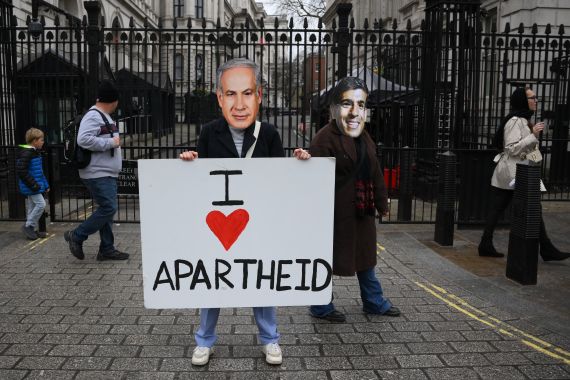 Protesters wearing facemasks of Israel's Prime Minister Benjamin Netanyahu (L) and Britain's Prime Minister Rishi Sunak (R) stand with a placard outside the gates of Downing Street in central London on March 23, 2023. - Amnesty International UK activists staged a protest against Israeli apartheid outside Downing Street on Thursday afternoon as the Israeli prime minister Benjamin Netanyahu visits the UK for talks with Rishi Sunak. (Photo by Daniel LEAL / AFP)