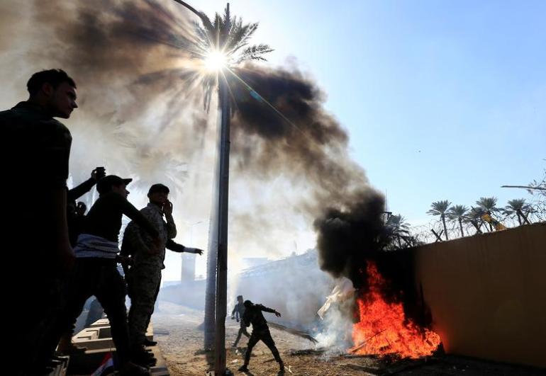 عناصر الحشد الشعبي تضرم النيران قرب السفارة الأميركية ببغداد لإدانة الضربات الجوية على قواعدهم - رويترز