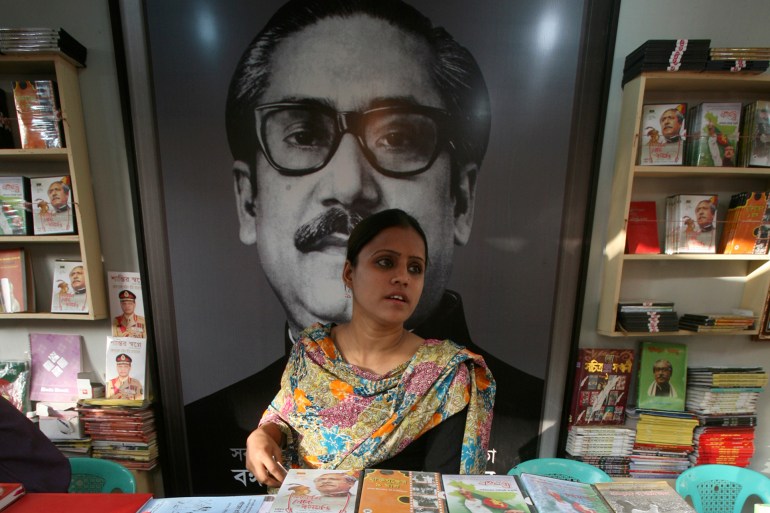 A sales person stands in front of a picture of independence leader Sheikh Mujibur Rahman in a stall at a book fair in Dhaka February 23, 2009. The Ekushey book fair is traditionally organized in the memory of those who died for the Bangla Language Movement ,which aimed to establish Bengali as one of the state languages of former united Pakistan. REUTERS/Andrew Biraj (BANGLADESH)