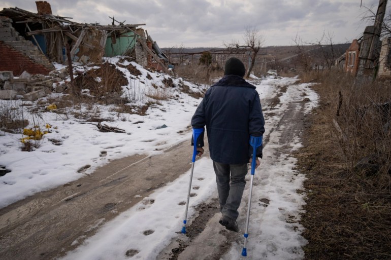 Andrii Cherednichenko, 50, who was injured after stepping on a landmine, walks on a snowy path in Kamianka, Ukraine. [Vadim Ghirda/AP Photo]