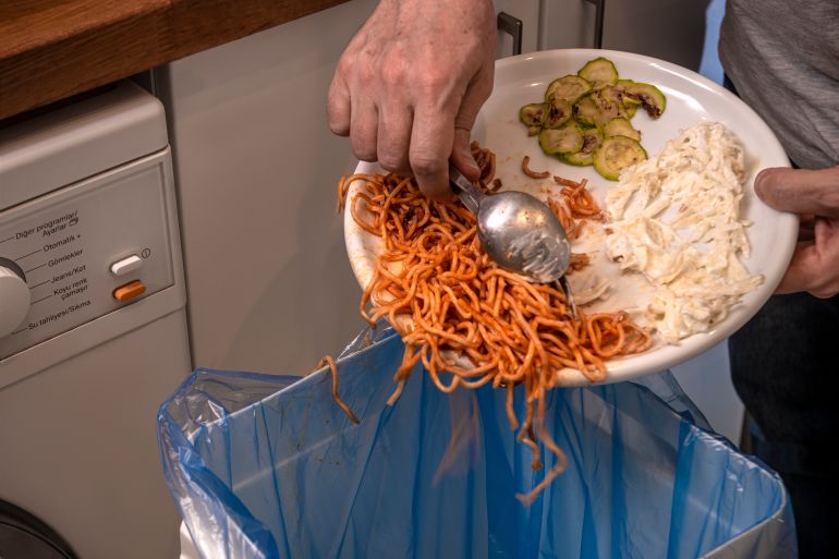 GettyImages-1215404946 Emptying pasta leftovers into rubbish bin.