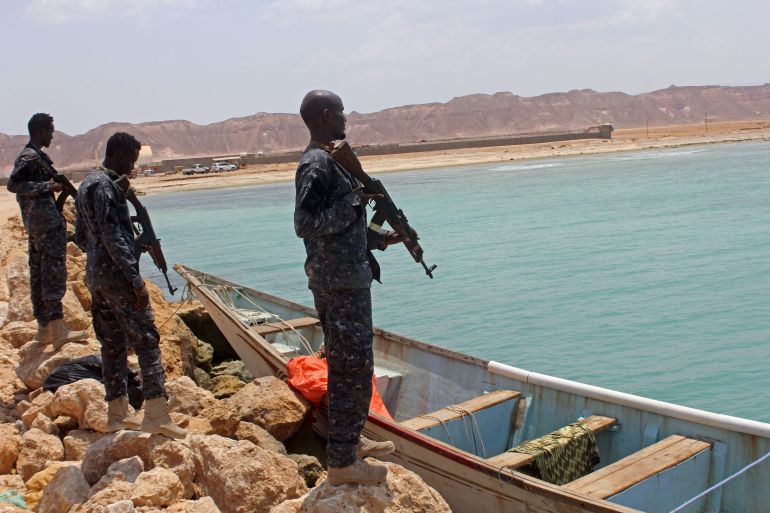 Somali Puntland forces guard a boat seized with weapons on the shores of the Gulf of Aden in the city of Bosasso