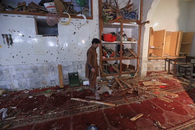 A man walks amid the damages at the prayer hall after a bomb blast inside a mosque during Friday prayers in Peshawar