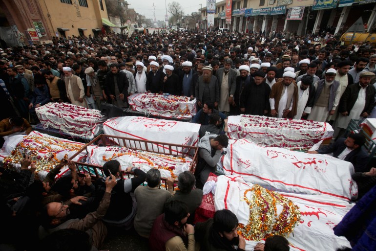 People gather around coffins of the victims killed after a bomb blast inside a mosque during Friday prayers, as they attend a funeral, in Peshawar