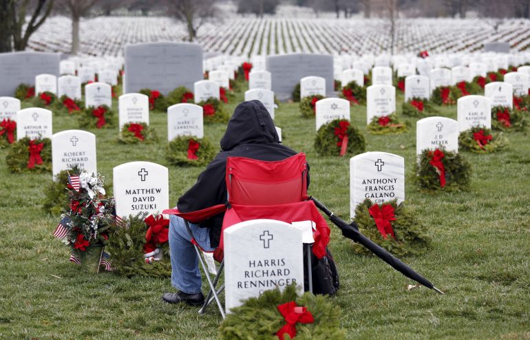 Sitting among graves adorned with holiday wreaths, Andrew Suzuki of Warrenton, visits the grave of his son Matthew Suzuki on the third anniversary of his death at Arlington National Cemetery's Section 60 in Virginia