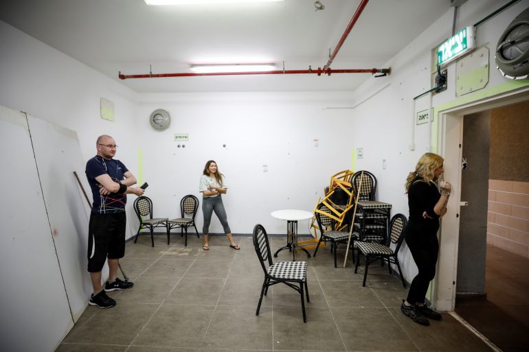 People stand inside a bomb shelter as a siren warning of incoming rockets launched from the Gaza Strip towards Israel sounds, in Ashkelon