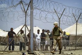 FILE PHOTO: FILE PHOTO: A U.S. soldier walks past Iraqi detainees standing behind a wired fence, at Abu Ghraib prison outside Baghdad, Iraq May 17, 2004. Security concerns and outrage at the treatment of Iraqi prisoners at a jail west of Baghdad have piled up pressure on the U.S.-led occupiers and threatened President Bush's bid for re-election in November. REUTERS/Damir Sagolj/File Photo/File Photo
