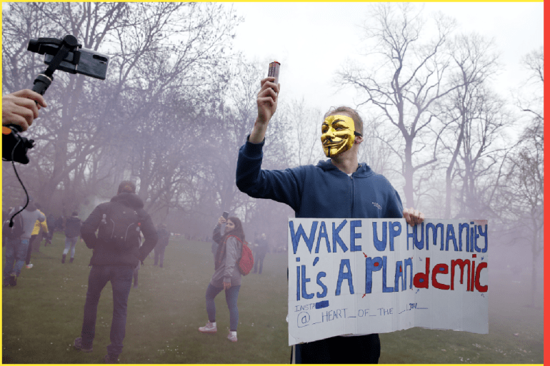 LONDON, ENGLAND - MARCH 20: A protester with a flare poses holding a sign calling for people to "wake up" during a "World Wide Rally For Freedom" protest on March 20, 2021 in London, England. "World Wide Rally For Freedom" protests, with apparent links to the QAnon conspiracy-theory movement, are being held in cities across the globe this weekend, decrying both pandemic-era lockdown measures and covid-19 vaccination campaigns. Police warned protesters in London ahead of this weekend's event that they face arrest under public-health laws preventing more than two people from different households from mixing. (Photo by Hollie Adams/Getty Images)
