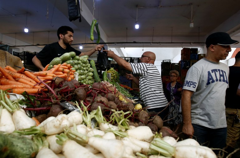 People shop for vegetables and fruits at a market in Algiers