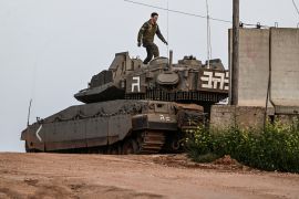 An Israeli soldier walks on top of a tank near Shtula, by the Israel Lebanon border in northern Israel