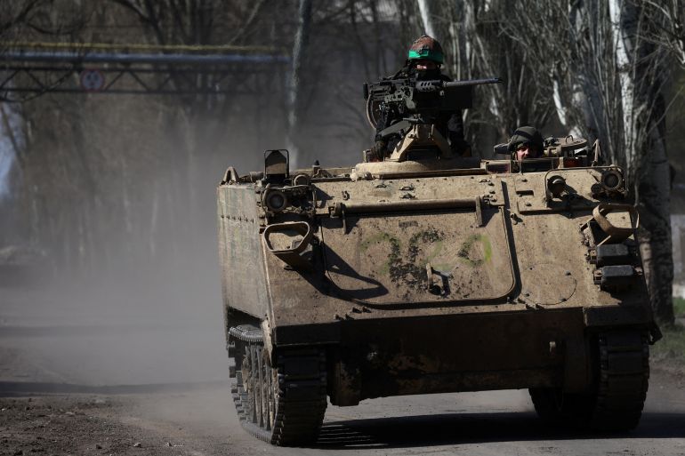 An armoured military vehicle speeds through Chasiv Yar