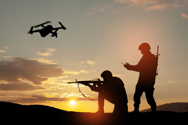 Silhouettes of soldiers are using drone and laptop computer for scouting during military operation against the ...