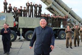 North Korean leader Kim Jong-un celebrating the test-firing of a 'newly developed super-large multiple rocket launcher' at an undisclosed location. AFP