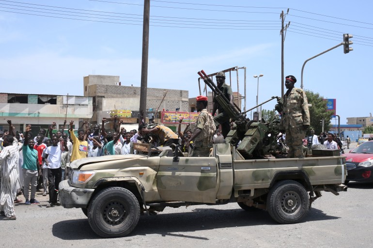 Sudanese greet army soldiers, loyal to army chief Abdel Fattah al-Burhan, in the Red Sea city of Port Sudan on April 16, 2023. - Battling fighters in Sudan said they had agreed to an hours-long humanitarian pause, including to evacuate wounded, on the second day of raging urban battles that killed more than 50 civilians including three UN staff and sparking international outcry. (Photo by - / AFP)