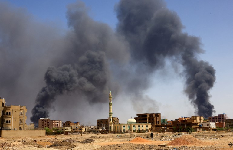 Smoke rising from building after aerial bombardment in Khartoum North, man walks