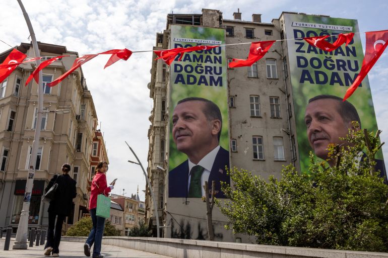 People walk next to posters of Turkish President Tayyip Erdogan in Istanbul