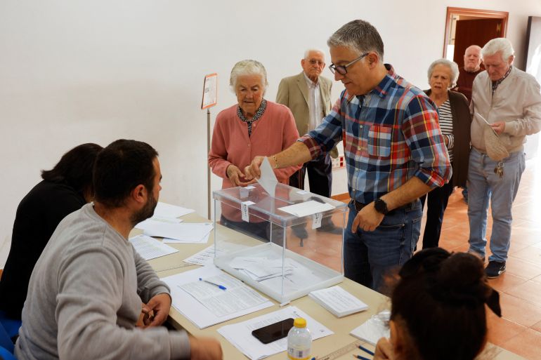 A man helps his mother to cast her vote at a polling station during local elections, in Ronda