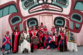 Tlingit dancers stand in front of the Totem House.