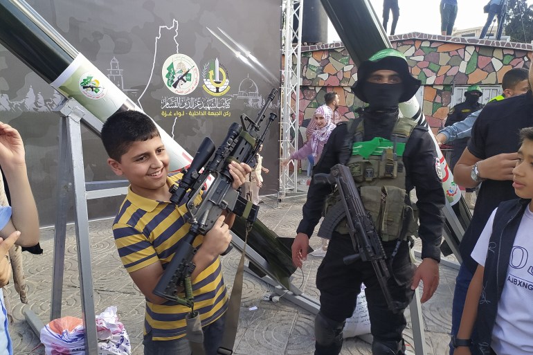 طفل فلسطيني سعيد بحمل بندقية من طراز M16 في معرض للأسلحة نظمته كتائب القسام في غزة-رائد موسى-الجزيرة نت