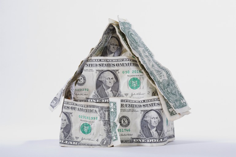 SOLD signboard on a miniature house made up of US dollar bills GettyImages-82959584