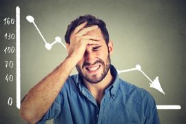 Portrait frustrated stressed young man desperate with financial market chart graphic going down on grey office wall background. Poor economy financial crisis concept. Face expression, emotion shutterstock_326260910