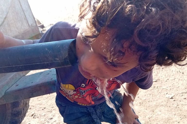 فاطمة محمود الأغوار الشمالية الجزيرة نت،طفل من خربة مكحول يشرب الماء من صهريج المياة خلال موجة الحر الشديدة
