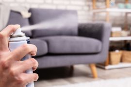 Close-up Of A Human's Hand Spraying Air Freshener In Living Room