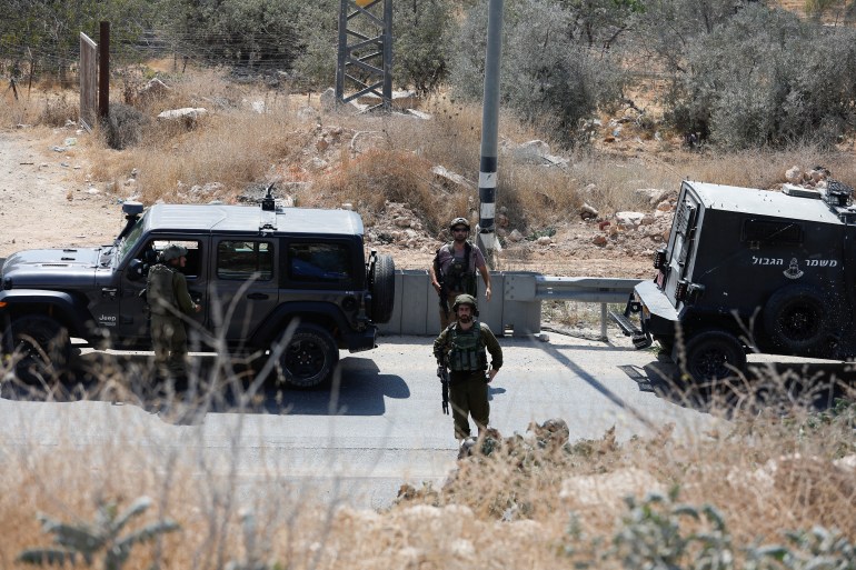 Israeli troops stand guard, at the scene of a shooting, near Hebron, in the Israeli-occupied West Bank August 21, 2023. REUTERS/Mussa Qawasma