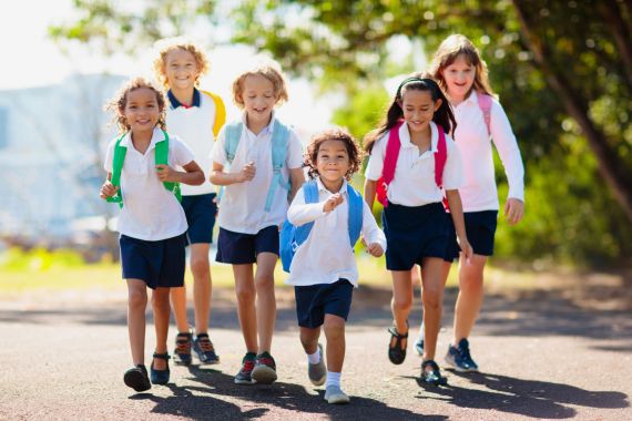 Kids back to school. Group of children. - stock photo Kids go back to school. Interracial group of children of mixed age run and cheer on the first day of new academic year. Start of school holiday. Preschooler or kindergarten kid. Child in school yard.