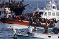 An Italian Coast Guard boat carries migrants as tourists on boat, foreground, watch, near the port of the Sicilian island of Lampedusa, southern Italy, Monday, Sept. 18, 2023. (Cecilia Fabiano/LaPresse via AP)
