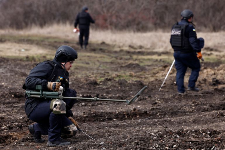 Members of the de-mining department of the Ukrainian Emergency Services survey an area of farmland and electric power lines for land mines and other unexploded ordnance for electricians to access power towers damaged by Russian strikes in order to repair them, amid Russia's invasion of Ukraine, in Korovii Yar, in the Eastern Donetsk region, Ukraine, March 20, 2023. REUTERS/Violeta Santos Moura