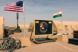 FILE- In this file photo taken Monday, April 16, 2018, a U.S. and Niger flag are raised side by side at the base camp for air forces and other personnel supporting the construction of Niger Air Base 201 in Agadez, Niger. As extremist violence grows across Africa, the United States is considering reducing its military presence on the continent, a move that worries its international partners who are working to strengthen the fight in the tumultuous Sahel region. (AP Photo/Carley Petesch, File)