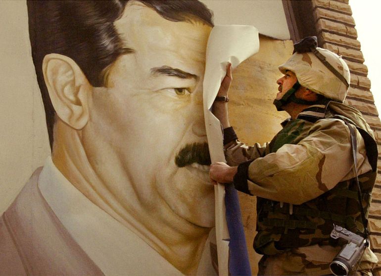 SAFWAN, IRAQ - MARCH 21: (NEWSWEEK AND U.S. NEWS OUT UNTIL 4/7/03) U.S. Marine Major Bull Gurfein pulls down a poster of Iraqi President Saddam Hussein March 21, 2003 in Safwan, Iraq. Chaos reigned in southern Iraq as coalition troops continued their offensive to remove Iraq's leader from power. (Photo by Chris Hondros/Getty Images)
