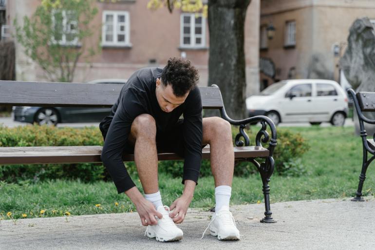 Man tying shoelaces on bench