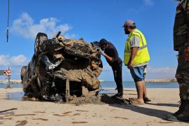 فريق إنقاذ يتفقد سيارة جرفتها المياه إلى البحر أثناء الفيضانات التي ضربت درنة اللبيبة (الفرنسية)