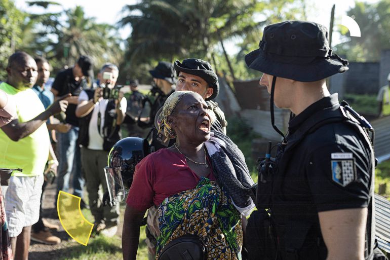 A woman yells to a French gendarme during the demolition of an informal settlement in Longoni, Mamoudzou, on the island of Mayotte on April 27, 2023. (Photo by Patrick Meinhardt / AFP)