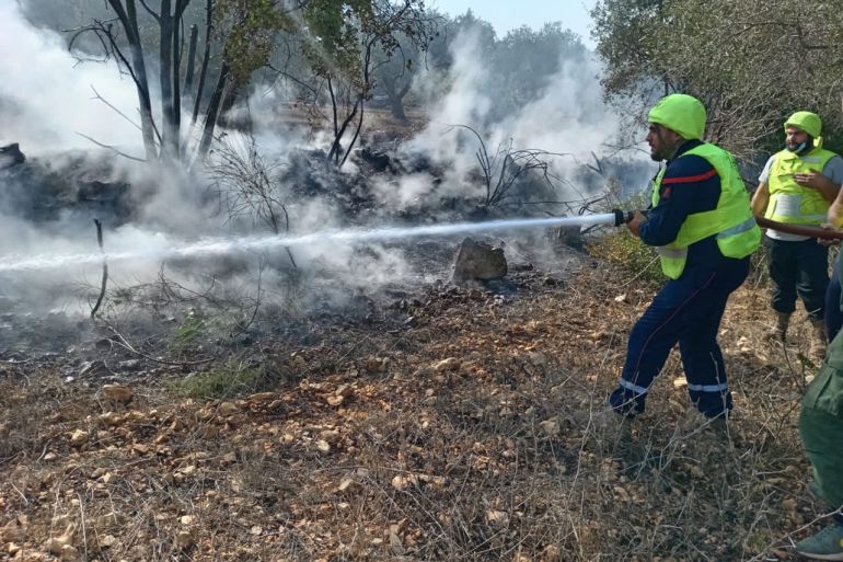)تصوير الدفاع المدني (عناصر الإطفاء في الدفاع المدني تقوم بإطفاء النيران في الأحراش وبساتين الزيتون اللبنانية