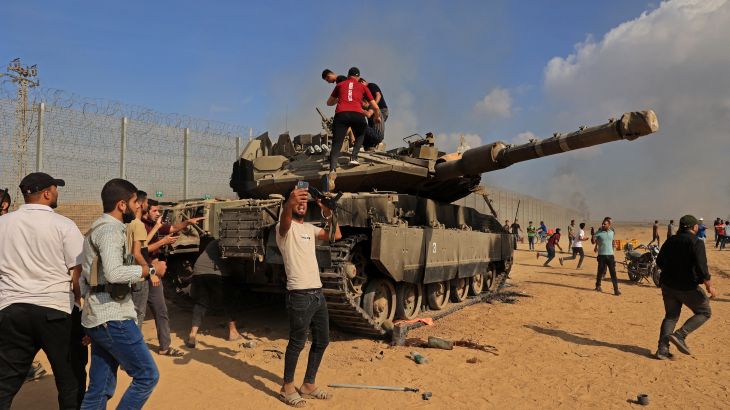 Palestinians take control of an Israeli tank after crossing the border fence with Israel from Khan Yunis in the southern Gaza Strip on October 7, 2023. - Barrages of rockets were fired at Israel from the Gaza Strip at dawn as militants from the blockaded Palestinian enclave infiltrated Israel, with at least one person killed, the army and medics said. (Photo by SAID KHATIB / AFP)