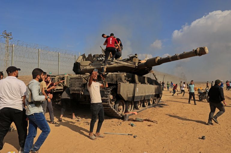 Palestinians take control of an Israeli tank after crossing the border fence with Israel from Khan Yunis in the southern Gaza Strip on October 7, 2023. - Barrages of rockets were fired at Israel from the Gaza Strip at dawn as militants from the blockaded Palestinian enclave infiltrated Israel, with at least one person killed, the army and medics said. (Photo by SAID KHATIB / AFP)