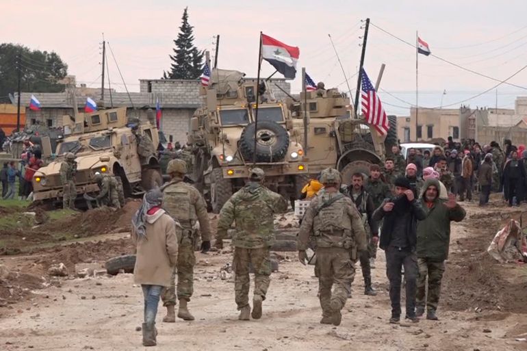FILE - In this Feb. 12, 2020, file frame grab from video, Russian, Syrian and others gather next to an American military convoy stuck in the village of Khirbet Ammu, east of Qamishli city, Syria. In a world gripped by a pandemic, global unrest and a fast-moving news cycle, it can be difficult to remember that the war in Syria is still happening. (AP Photo/File)