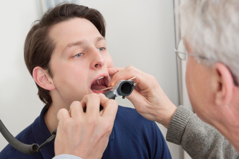 Young man getting his throat checked by male doctor at clinic