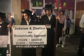 متظاهرون يهود بالزي الديني الرسمي يرفعون لافته ان الصهيونية ضد اليهودية وان اليهودية دين ولكن الصهيونية جنسية