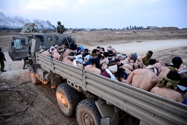 Israeli soldiers stand by a truck packed with shirtless Palestinian detainees, amid the ongoing conflict between Israel and the Palestinian Islamist group Hamas, in the Gaza Strip December 8, 2023. REUTERS/Yossi Zeliger ISRAEL OUT. NO COMMERCIAL OR EDITORIAL SALES IN ISRAEL TPX IMAGES OF THE DAY EDITOR'S NOTE: REUTERS PHOTOGRAPHS WERE REVIEWED BY THE IDF AS PART OF THE CONDITIONS OF THE EMBED. NO PHOTOS WERE REMOVED.
