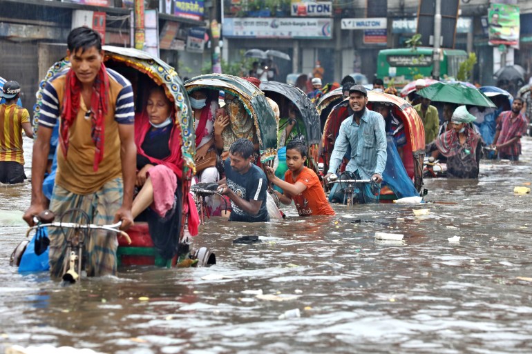 Dhaka, Bangladesh - July 21, 2020: Vehicles try to drive through a flooded street in Dhaka. Encroachment of canals ...