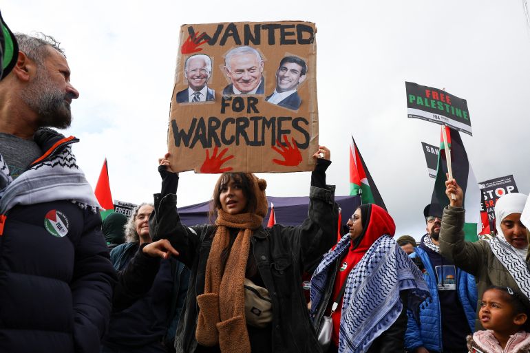 A demonstrator holds up a sign featuring images of U.S. President Joe Biden, Israeli Prime Minister Benjamin Netanyahu and British Prime Minister Rishi Sunak, at a protest in solidarity with Palestinians in Gaza, amid the ongoing conflict between Israel and the Palestinian Islamist group Hamas, in London, Britain, October 21, 2023. REUTERS/Hannah McKay