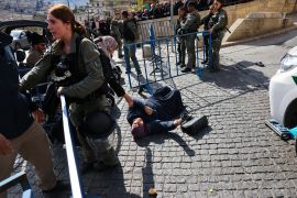 A woman lays on the ground after falling as Muslim worshippers wait at an Israeli checkpoint near Lion's Gate to enter the Al-Aqsa Mosque compound for the Friday Noon prayer in Jerusalem on January 5, 2024, amid the ongoing battles between Israel and the Palestinian group Hamas. (Photo by AHMAD GHARABLI / AFP)