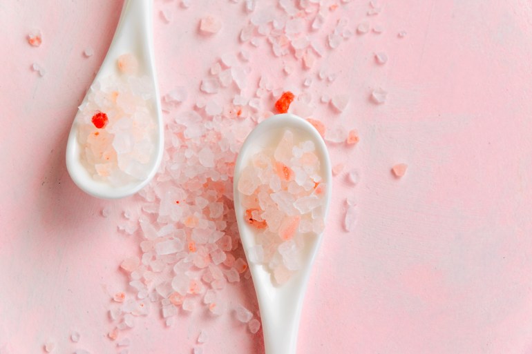 Close up view of white spoons with pink himalayan salt