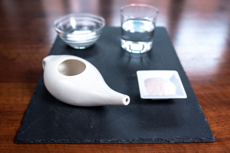 set for nasal cleaning with neti pot, ayurvedic medicine system, pink salt, sodium bicarbonate, water on a slate