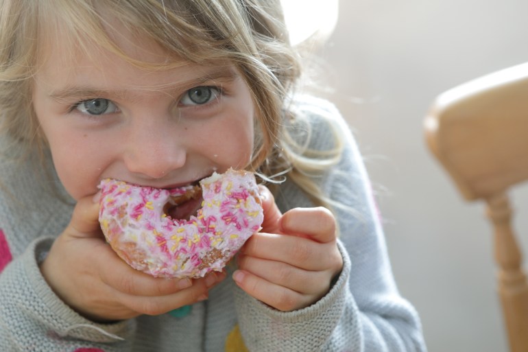 Young girl eating doughnut - stock photo