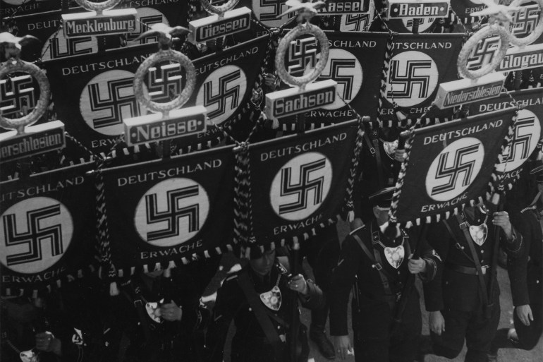 SS (Schutzstaffel - Engl. Protective Squadron) members carry flags with a swastika and names of German states and towns as they march towards the town hall of Nuremberg, Germany, September 10, 1935, to open the nationalists party convention of the Nationalsozialistische Deutsche Arbeiterpartei - NSDAP (National Socialist German Workers' Party). EDS note: Writing on flags is: Deutschland erwache - Germany wake up). (AP Photo)